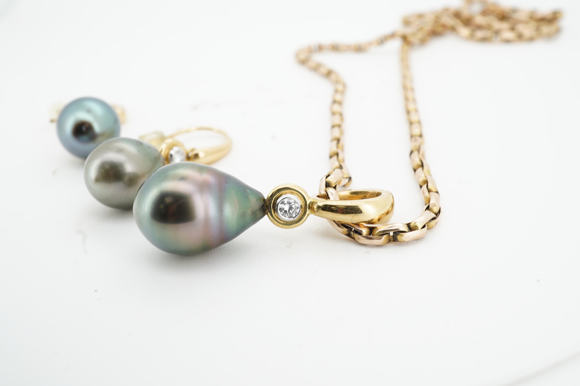 A cultured pearl and diamond demi-parure, comprising: a pendant, suspending a drop-shaped cultured pearl of black tint, measuring approximately 15 x 10.5 x 10.5mm, surmounted by a collet-set brilliant-cut diamond weighin